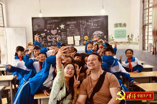 徐希定(图前左)在云南省凤庆县红塘村的一所小学与学生们互动交流_缩小大小.png